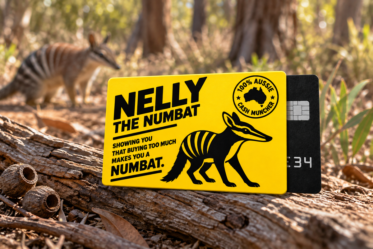 Nelly the Numbat yellow card sleeve resting on weathered Australian woodland timber with a blurred numbat and natural bushland in the background.